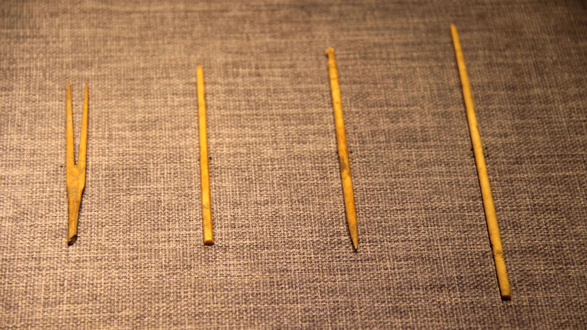 چهار سوزن باستانی طب سوزنی از دوره‌ی کشورهای در حال جنگ چین روی پارچه‌ی کتانی خاکستری؛ تصویری برای مقاله‌ی مدرک طب سوزنی معتبر